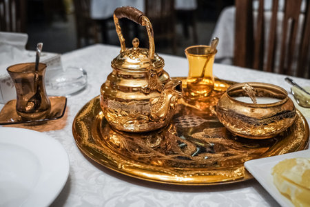 Close-up view of traditional Middle Eastern traditional Authentic arab tea set, vintage glass cups with teapot on the table at the restaurant. Old vintage oriental teapot with cups.の写真素材
