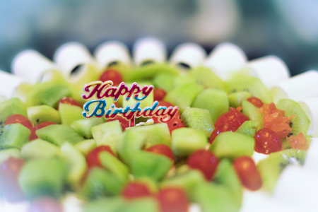 Birthday sweet cake close up. Happy birthday fruit cake decorated with cherries and kiwi. Happy birthday wish on top of the cake. Selective focus, blurred, nobody.の写真素材