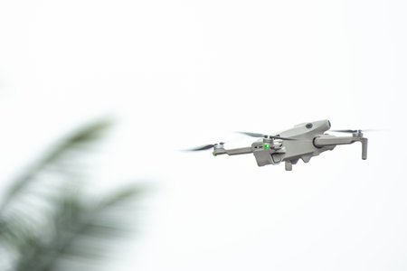 Modern drone with digital camera in the air. Drone with camera flies in the background of trees and...