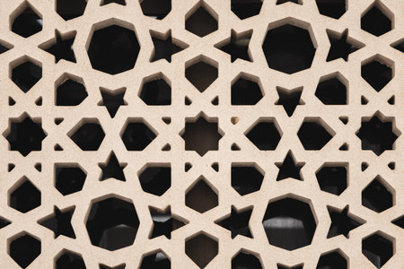 Intricate stone lattice jali design, geometric floral patterns carved into a beige wall, showcasing...