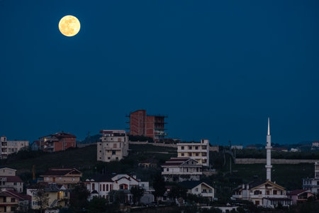 Moonrise in night sky. Full moon shines at night over small town in Balkans. travel photo, nobody, copy space. Astronomy conceptの写真素材