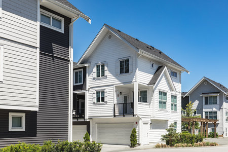 New townhouses in residential comfortable neighborhood on a sunny day. Real Estate Exterior Front Homes with garages in suburbs North America. Modern apartment buildings. Housing development
