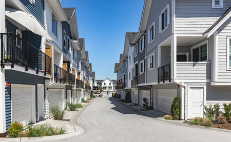 New townhouses in residential comfortable neighborhood on a sunny day. Real Estate Exterior Front Homes with garages in suburbs North America. Modern apartment buildings. Housing development