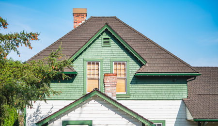 Countryside house with shingles roof tiles . Top of the wooden house with nice windows and chimney in rural Canada on a sunny day with blue sky. Nobody