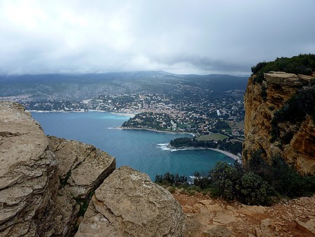 View of Cassis village and mediterranean sea, France, from the mountain between big red rocks with...