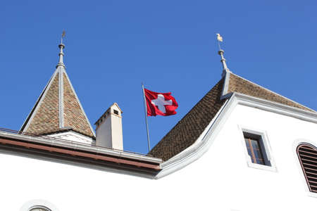 Swiss flag floating upon the roof of Nyon castle, Switzerlandの写真素材