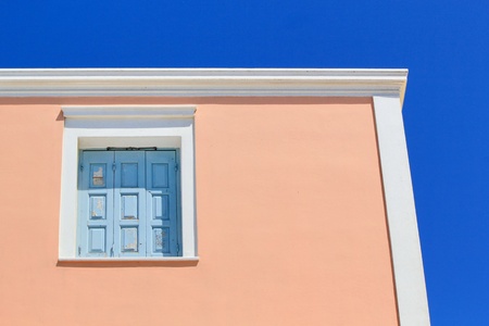Colorful facade of a house with its blue closed shutters, red facade by beautiful weather, Santorini, Greece の写真素材
