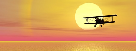 Old biplan flying upon ocean by sunsetの写真素材