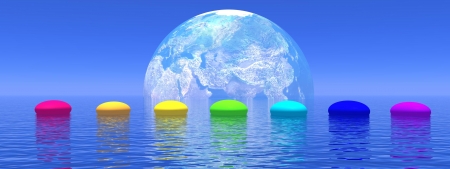 Line of seven pebbles with chakras colors upon the deep blue ocean, in front of earth shadow, horizon in the backgroundの写真素材