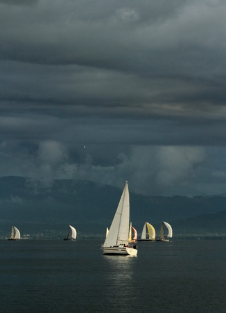 Colorful sailboat sailing on a calm evening with dramatic sunset, Geneva lake, Switzerlandの写真素材
