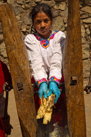 SIBAMBE, ECUADOR, 28 JUNE 2019. A woman in a national costume squeezes sugarcane juice at the Sibambe railway station, Ecuador.のeditorial素材