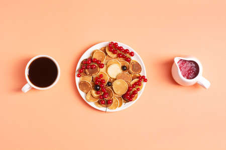 Delicious mini bags in a white plate with red and black currants on a peach background, next to a...