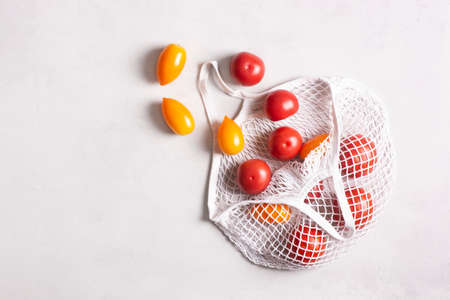 Eco-friendly mesh bag with tomatoes on a gray surface, flat lay, top view. Zero waste, no plastic concept.の写真素材