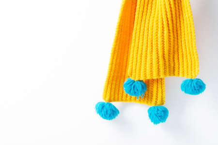 Yellow knitted scarf hanging on a white background. Close-up, selective focus. Horizontal...