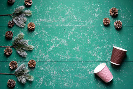 Winter festive concept, cones, fir branches, colorful paper cups on green wooden background with...