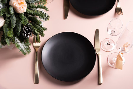 Beautiful table setting for a celebration for two, black plate and glasses with flower arrangement...