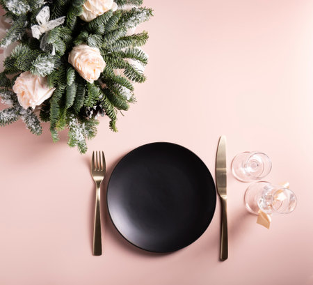 Festive beautiful table setting, black plate and glasses with flower arrangement on powdery background, flat lay, copy spaceの写真素材