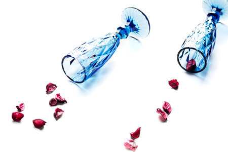 Beautiful empty glasses for wine or champagne lie with petals on a white background, horizontal orientationの写真素材