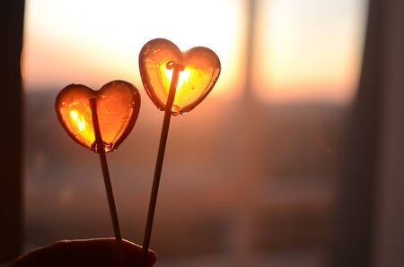 two transparent lollipop hearts on sunset backgroundの写真素材