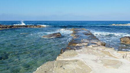 rocky shore of the blue sea, waves, white foamの写真素材