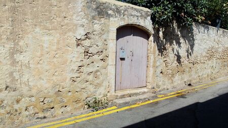 old door in the stone wall by the roadの写真素材