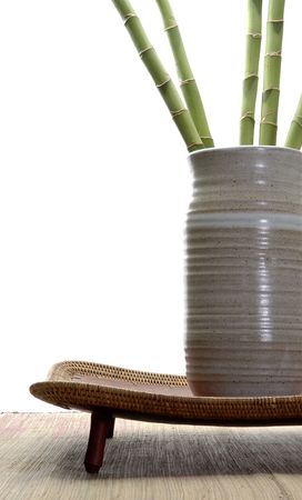 Ornamental bamboo in a neutral tone hand thrown vase sitting on an asian style tray.の写真素材