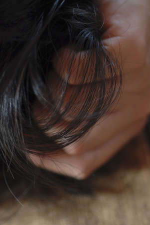Detail of dark hair with hand wrpped around it. の写真素材