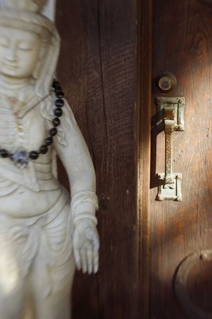 Rustic Asian style door with buddhis statue. Focus on the handle. Lensbaby  soft focus image. の写真素材
