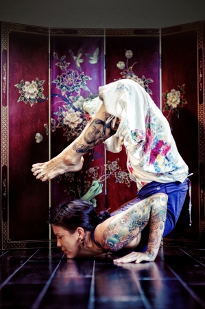 Dark haired woman doing scorpion pose in front of an asian panel の写真素材