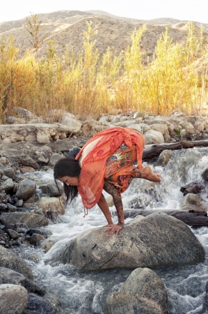 Woman outdoors in yoga pose bakasana in a mountain river  の写真素材