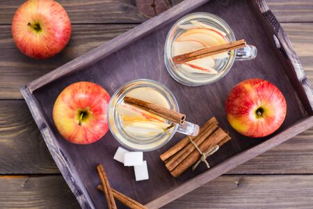 Warm soothing tea made from apples and cinnamon in glasses and ingredients for cooking on a wooden table. Detox concept, antidepressant. Rustic style. Top viewの写真素材