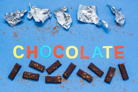 Pieces of chocolate, empty crumpled wrappers and the inscription chocolate sprinkled with cocoa...