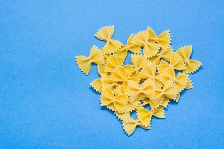 Raw farfale pasta on a blue cardboard background. Top viewの写真素材