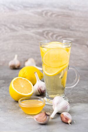 Therapeutic drink of lemon, honey and garlic in a glass on the table. Alternative medicineの写真素材