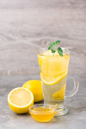 Therapeutic drink of lemon, honey and mint in a glass on the table. Alternative medicine, treatment with folk remedies.の写真素材