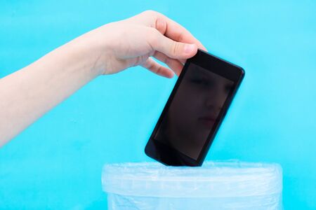 Digital detox concept. Children's hand throws a smartphone into the trash. Gadget addiction