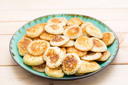 Trend breakfast. Dutch mini pancakes on plate on a wooden table. Close-upの写真素材