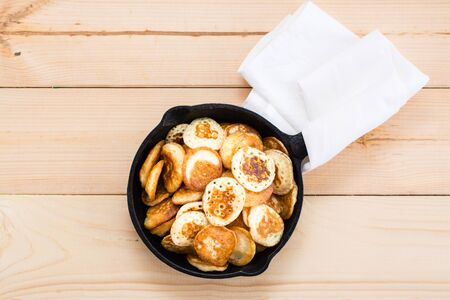 Trend breakfast. Dutch mini pancakes in a pan close-up on a wooden table. Top viewの写真素材
