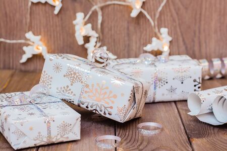 Wrapped in festive packaging gift boxes tied with silver ribbon, a roll of wrapping paper and...