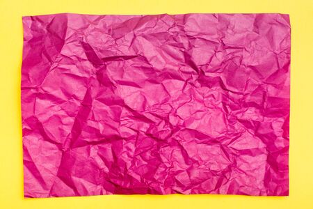 Blank crumpled purple sheet of colored paper on a yellow cardboard background. Textural motley background. Top view. Copy spaceの写真素材