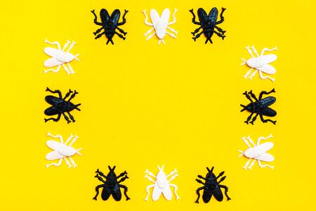 White and black plastic flies make up the frame on a yellow cardboard background. Ready Halloween invitation. Copy spaceの写真素材