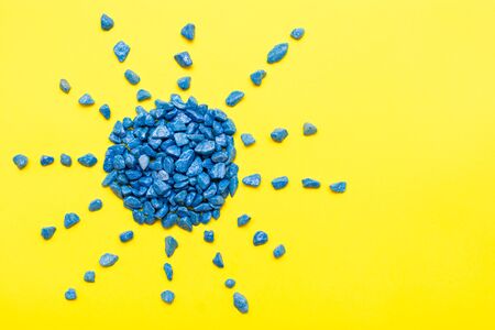 Blue decorative stones laid out in the shape of the sun on a yellow background