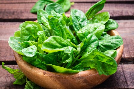 Fresh baby spinach leaves in a bowl on a wooden table. Close-up of herbesの写真素材
