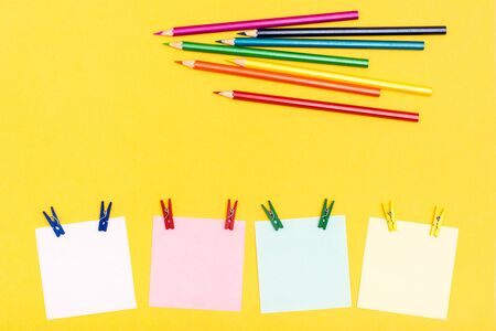 Sheets for writing pinned pins and colored pencils on a yellow background. Rainbow paletteの写真素材
