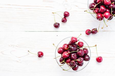 Fresh ripe sweet cherries in water drops in bowls on a white wooden table. Copy space. Top viewの写真素材