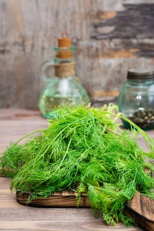 A bunch of fresh dill on a cutting board on a wooden table. Fragrant seasoning in rustic styleの写真素材