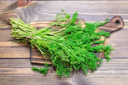 A bunch of fresh dill on a cutting board on a wooden table. Top viewの写真素材
