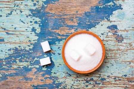 Sugar granulated and refined sugar in a bowl on a wooden table. Top viewの写真素材