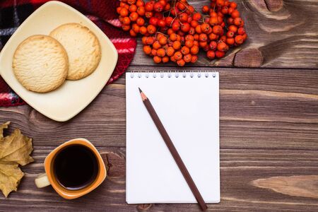 Autumn still life - coffee, cookies, a plaid, a notebook and a pencil on a wooden background. Top viewの写真素材