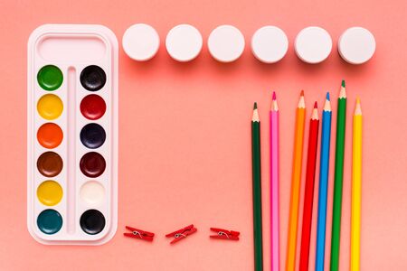 Accessories for drawing - pencils, watercolor and gouache on a red background. Top View. Copy spaceの写真素材